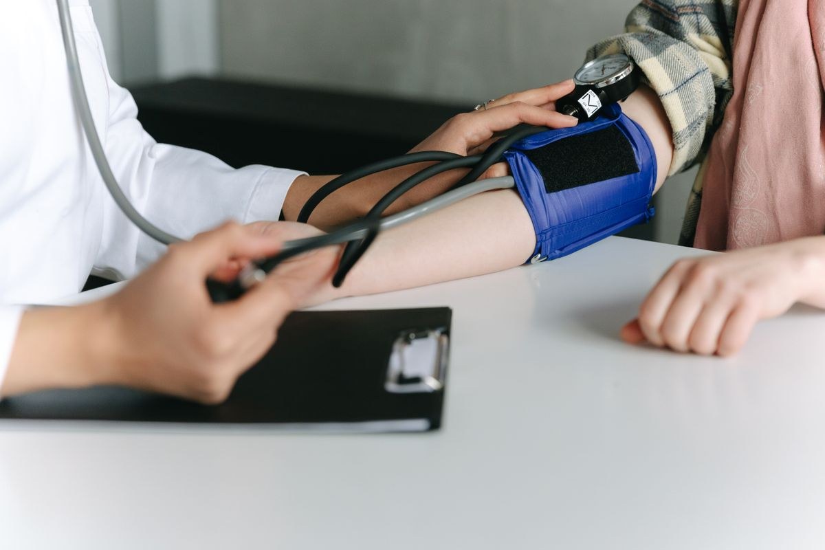 Manual blood pressure cuff and gauge on a patient arm at a clinic table